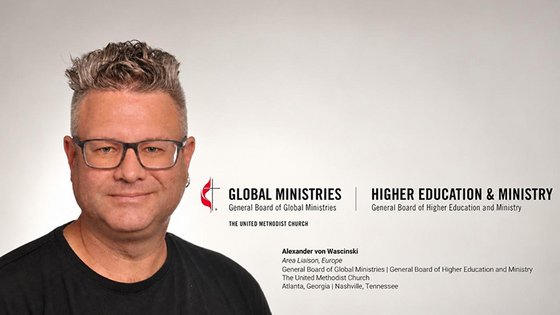 Links ein Mann mittleren Alters mit gegelten Haaren und Ohrring links sieht durch eine Brille freundlich direkt in die Kamera. Rechts das Logo der E m K und die Namen zweier Generalbehörden. Darunter der Name des Mannes und seine neue Stellenbezeichnung.
