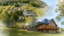 Das Bild ist eine Collage aus zwei Fotos: Oben links ein Luftbild vom Schwarzenshof, der in einer parkähnlichen Landschaft am Waldrand liegt. Unten rechts das ehemalige Backhaus mit großen Fenstern und einer Holzveranda.
