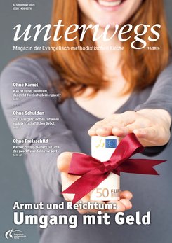 unterwegs-Ausgabe 18/2026 Im Vordergrund hält eine Person mit orangefarbenem Oberteil ein Geschenk, das aus einem 50-Euro-Schein besteht und mit einer weißen Schleife sowie einem kleinen blauen Geschenkanhänger verziert ist. Im Hintergrund ist der Oberkörper der Person unscharf zu erkennen. Oben steht der Schriftzug 'unterwegs', darunter weitere Angaben zum Magazin der Evangelisch-methodistischen Kirche. Auf der linken Seite sind drei Themenüberschriften zu sehen: 'Ohne Kamel', 'Ohne Schulden', 'Ohne Pressschlild'. Unten steht in weißer und gelber Schrift: 'Armut und Reichtum: Umgang mit Geld'.