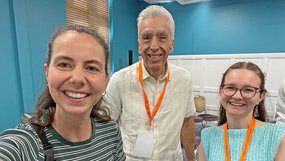 Lea Schmidt (links, gestreiftes Shirt), Bischof Ruben Saenz Jr. (Mitte, weißes Hemd) und Imke Sewing (rechts, hellblaues Oberteil) stehen bei der Global Young People’s Convocation in Dublin zusammen. Alle drei lächeln in die Kamera.